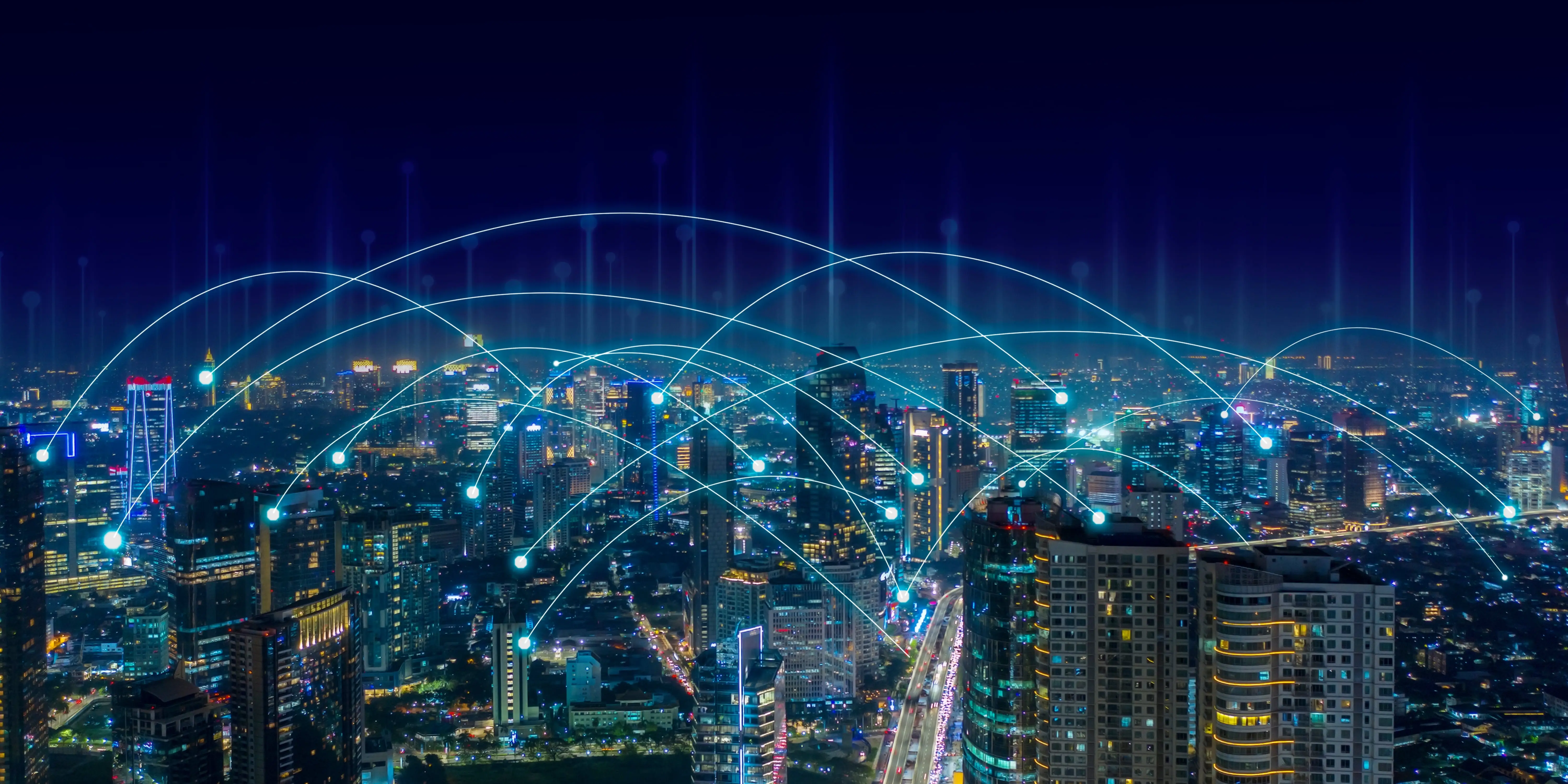 都市の夜景と、デジタルネットワークを象徴する青い光のラインが交差するイメージ